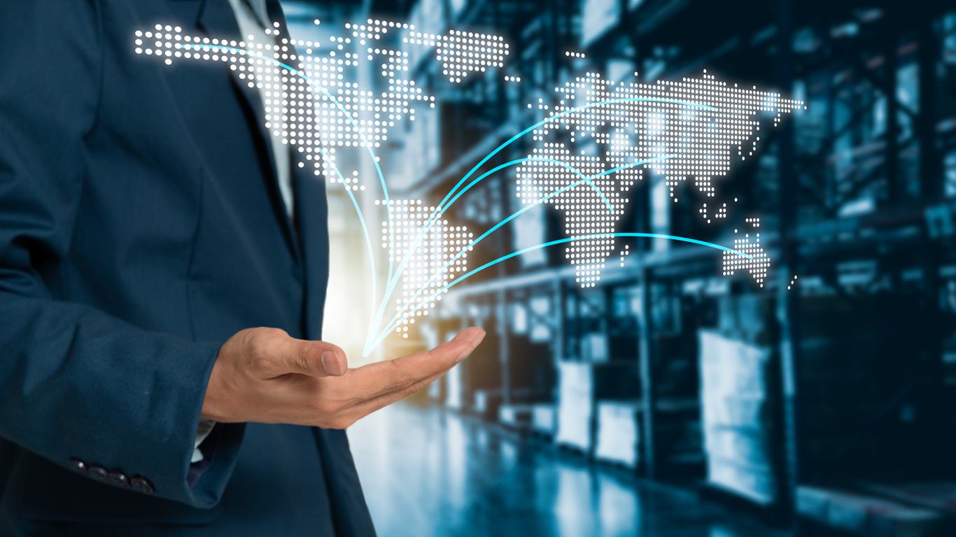 Businessman holding a digital world map above a warehouse